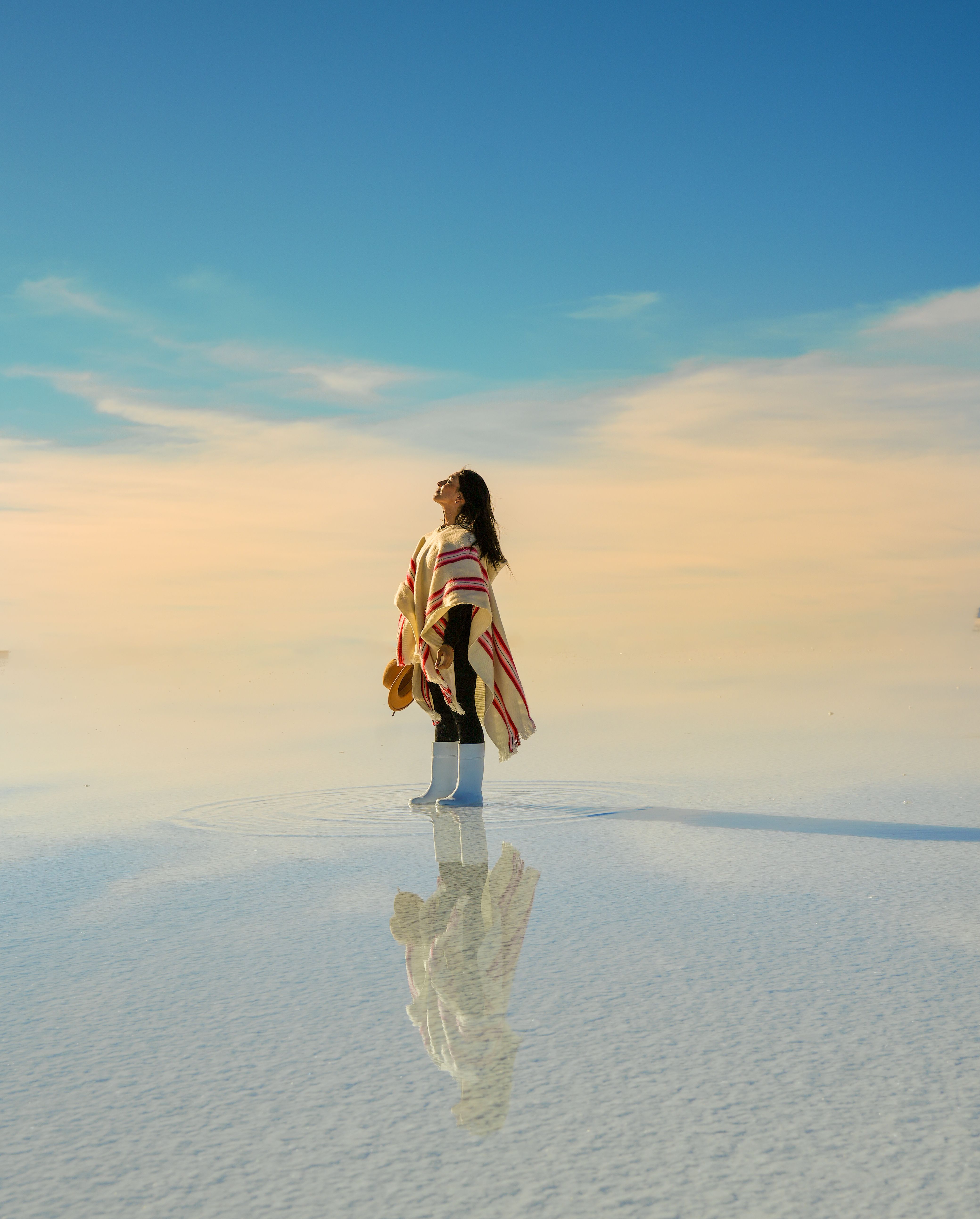 Kelly de pie sobre el Salar de Uyuni al amanecer, con un poncho de rayas.